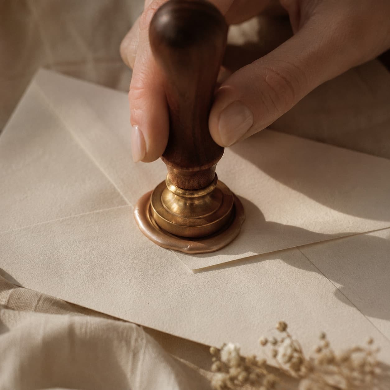 Pressing a brass stamp into warm wax to seal an envelope